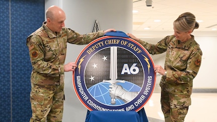 Two service members uncover the new logo.