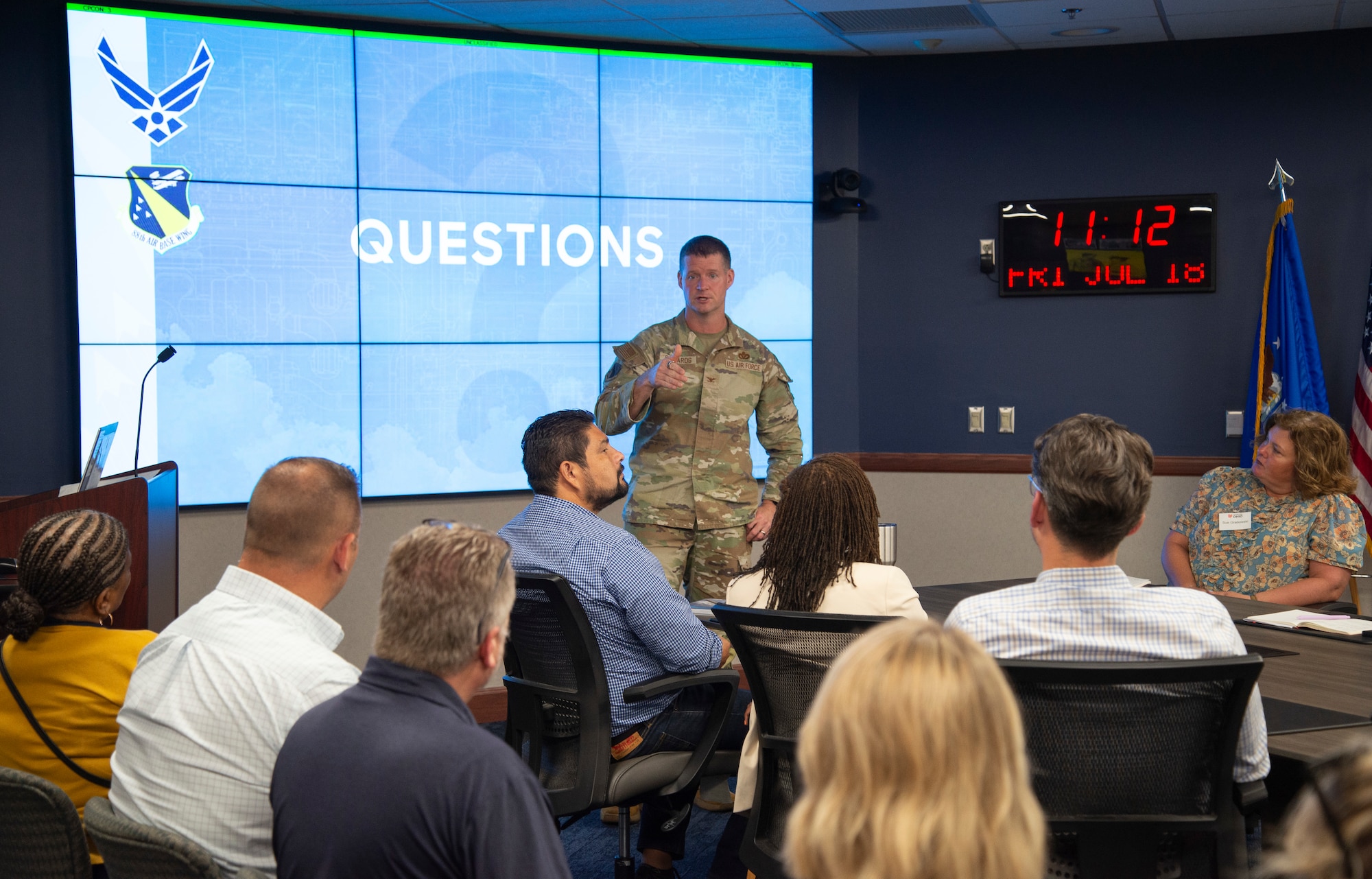 An individual military member talking to a group of individuals while giving a presentation.