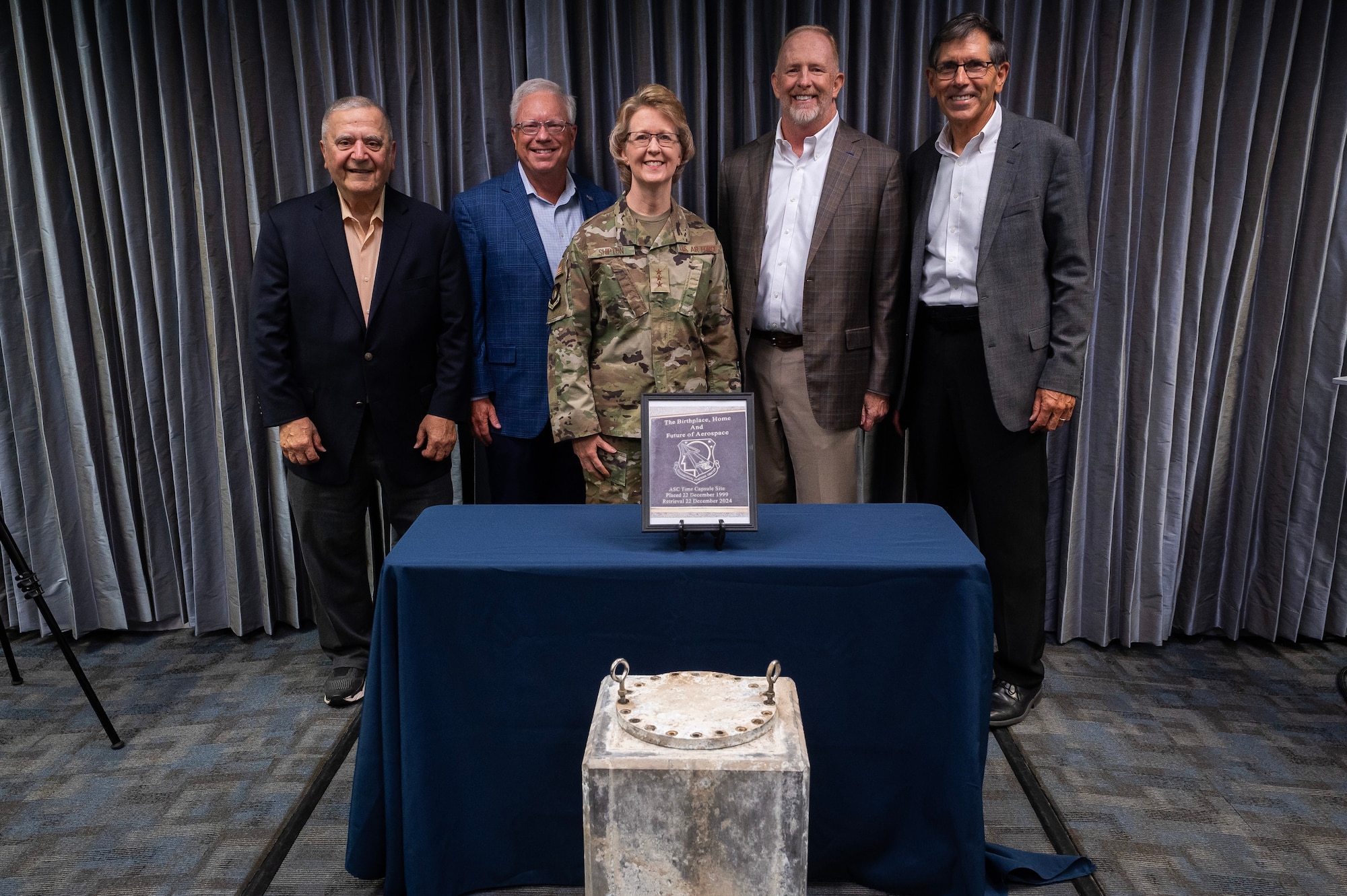 Group of individuals standing behind table.
