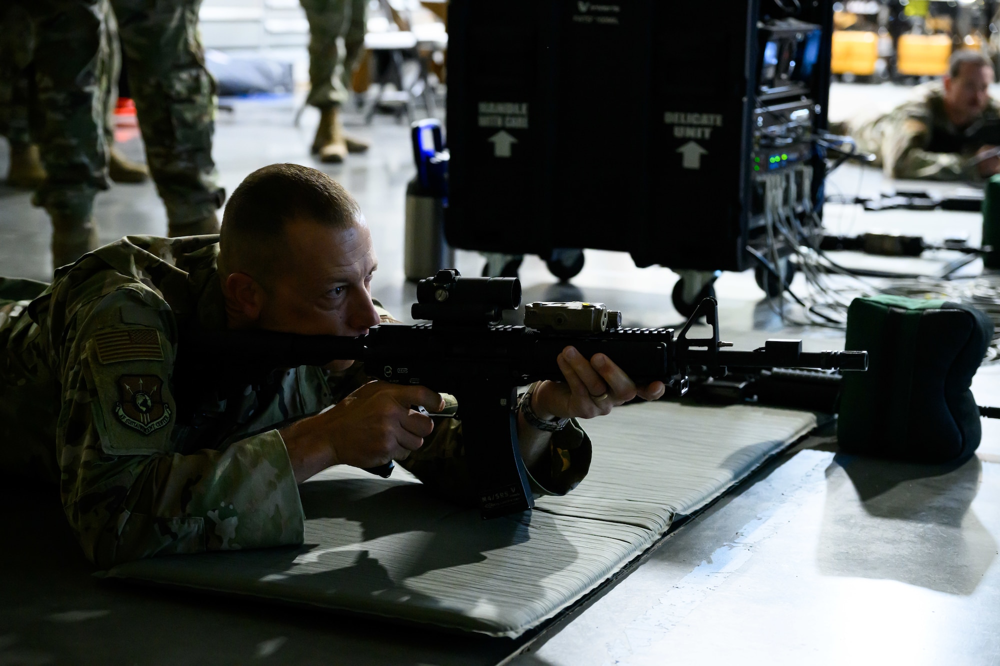 Chief Master Sgt. Carlos Labrador in a prone position aiming a simulated rifle.