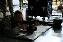 Chief Master Sgt. Carlos Labrador in a prone position aiming a simulated rifle.