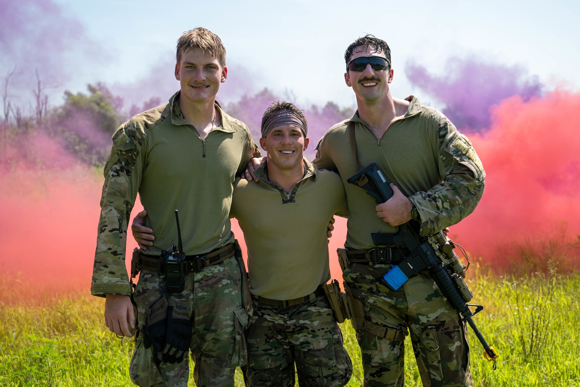 Three military men stand together in uniform to smile for a picture