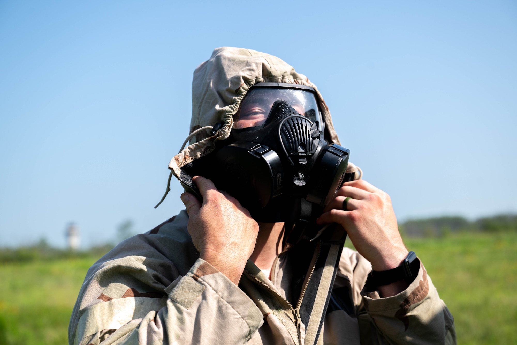 A man adjusts his gas mask and gear.