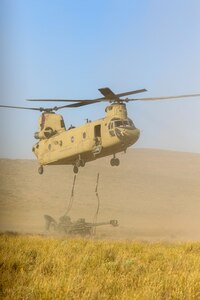 A Chinook Helicopter lifts an artillery piece during the Raven Focus exercise at Yakima Training Center, July 16, 2025. Active duty, U.S. Army Reserve and National Guard Soldiers participated in the training exercise to increase readiness for potential real-world deployments.