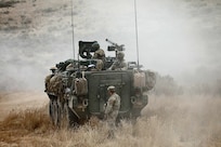 An observer coach/trainer, assigned to the 189th Combined Arms Training Brigade, stands by a Stryker vehicle preparing to move to a new position during the Raven Focus exercise, July 20, 2025, at the Yakima Training Center in Washington.