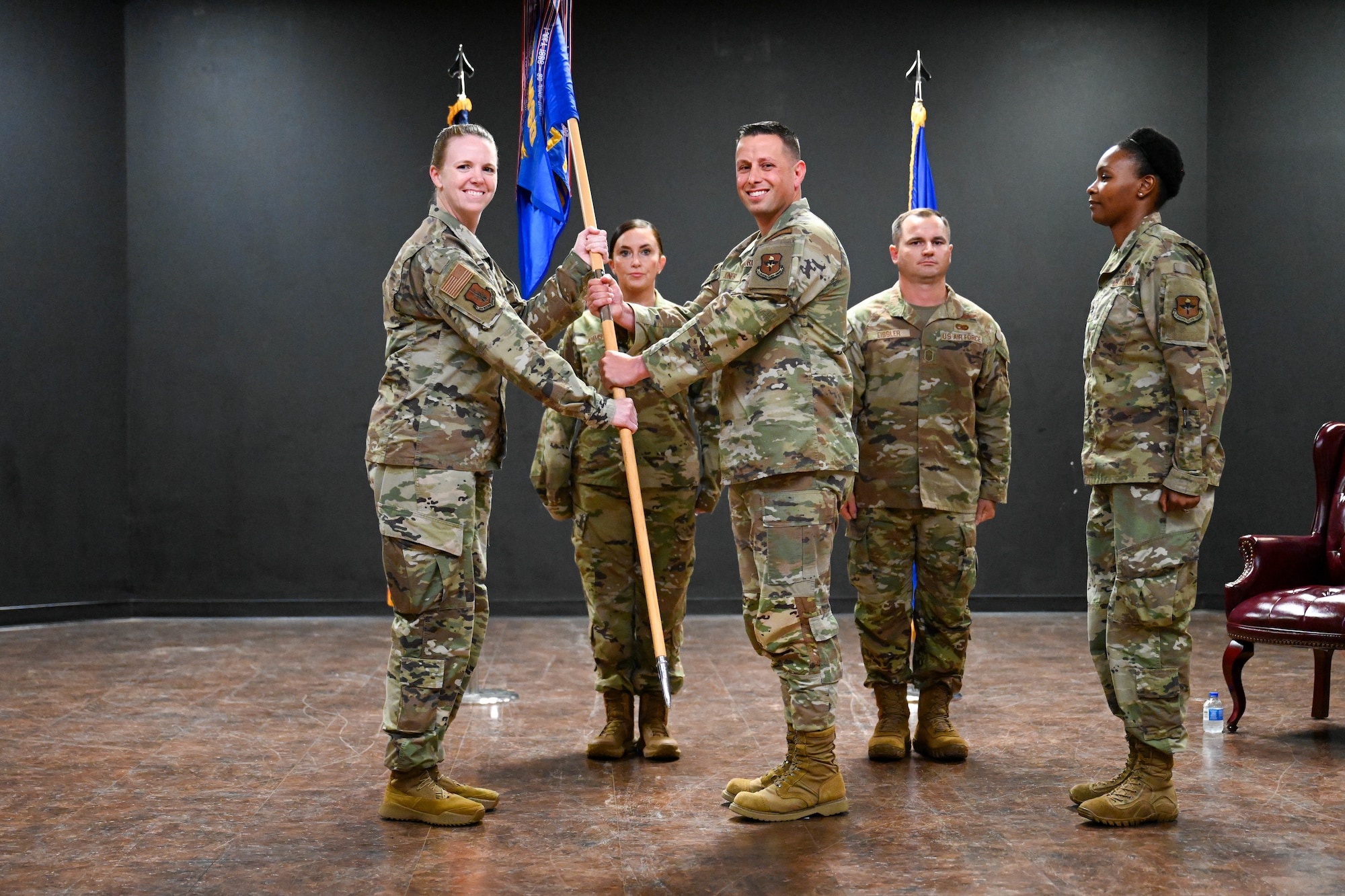 U.S. Air Force Col. Amanda Knotts, 97th Mission Support Group commander, passes the 97th Force Support Squadron (FSS) guidon to Major Aaron Jones, 97th FSS commander, at Altus Air Force Base, Oklahoma, July 19, 2025. The guidon was passed to Jones to signify the change of command for the 97th FSS. (U.S. Air Force photo by Airman 1st Class Nathan Langston)