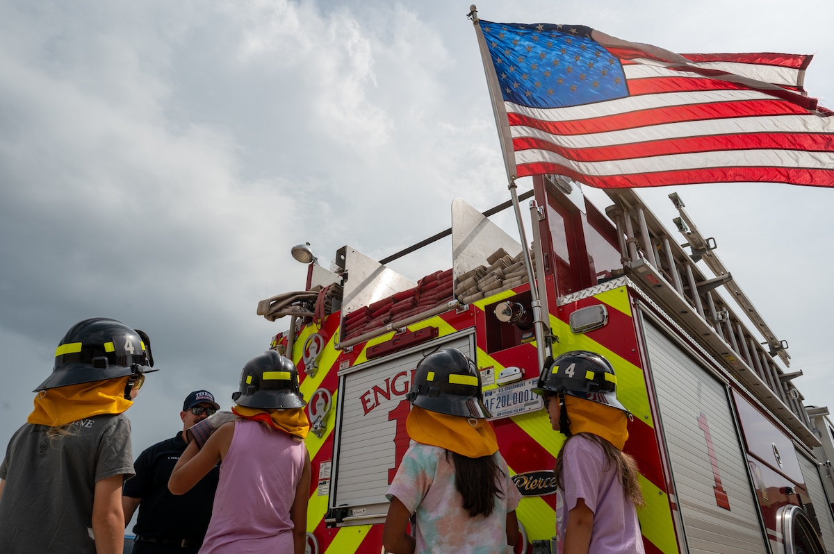 children look at fire truck with American flag