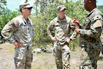 U.S. Army Capt. Chad Pickering, incoming Bilateral Affairs Officer (BAO), and U.S. Capt. Aaron Lies, outgoing BAO, speak with a Jamaica Defense Force (JDF) soldier at Moneague Training Camp, St. Ann, during the Caribbean Regional Training Camp 2025, held July 12-27 across Jamaica. The District of Columbia National Guard's (DCNG) partnership with Jamaica, facilitated by the U.S. National Guard Bureau's State Partnership Program, promotes security cooperation through military engagements and interagency collaboration.