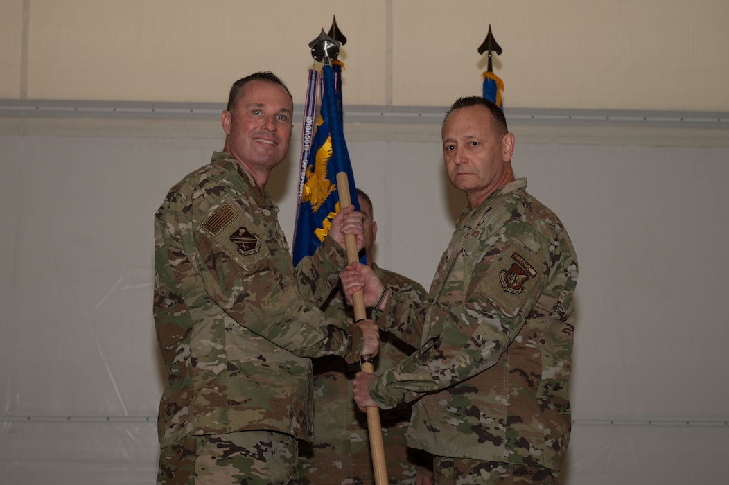 U.S. Air Force Col. Jerry Copeland, 354th Maintenance Group outgoing commander, right, relinquishes the guidon to Col. Michael Mullin, 354th Fighter Wing deputy commander, during a change of command ceremony at Eielson Air Force Base, Alaska, July 24, 2025.