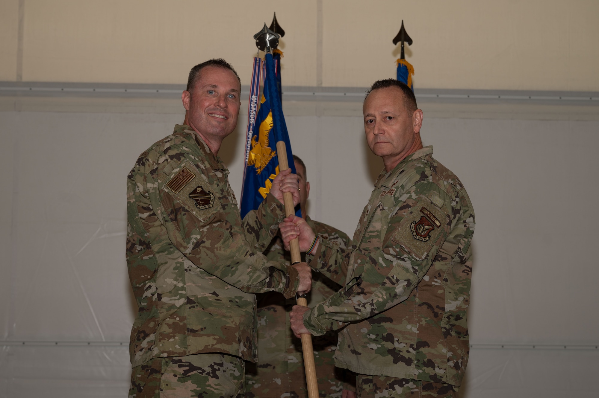 U.S. Air Force Col. Jerry Copeland, 354th Maintenance Group outgoing commander, right, relinquishes the guidon to Col. Michael Mullin, 354th Fighter Wing deputy commander, during a change of command ceremony at Eielson Air Force Base, Alaska, July 24, 2025.