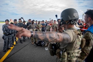 U.S. Air Force Airmen and Japan Air Self-Defense Force airmen assigned to the 3rd Air Wing learn loading techniques from U.S. Air Force Maj. David Stuppy, right in tactical gear, 18th Aeromedical Evacuation Squadron standardization and evaluation flight examiner, for a bilateral aeromedical evacuation training event during exercise Resolute Force Pacific (REFORPAC) 2025.