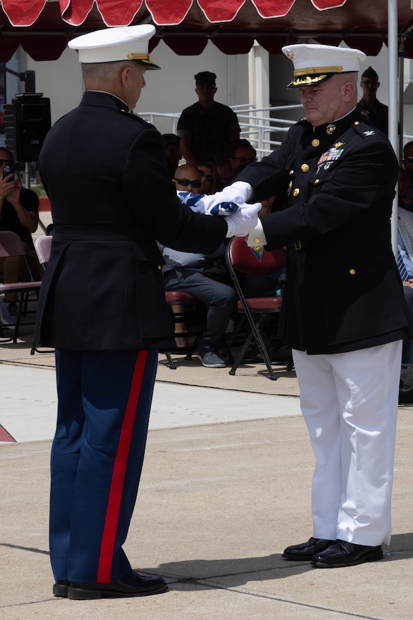U.S. Marine Corps Col. Kevin G. Hunter, right, the former commanding officer of Marine Aircraft Group 16, 3rd Marine Aircraft Wing, receives an American flag from Lt. Col. Samar M. Nashagh, a long range planning element liasion with Marine Corps Forces, Central Command, during the reading of Old Glory at his retirement ceremony at Marine Corps Air Station Miramar, California, July 18, 2025. Throughout his 26 years of honorable service, Hunter demonstrated consistent excellence with more than 3,100 mishap-free flight hours. His achievements earned him numerous commendations, including the Legion of Merit; Defense Meritorious Service Medal; Meritorious Service Medal with two gold stars; Individual Action Air Medal; Air Medal with Strike Numeral XIV; Joint Service Commendation Medal; Navy Commendation Medal; Navy and Marine Corps Achievement Medal with one gold star; and the Presidential Service Badge. (U.S. Marine Corps photo by Lance Cpl. Samantha Devine)