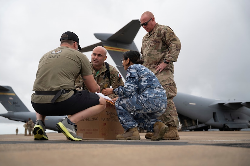 A U.S. Special Operations Forces Operator retrieves a cold chain blood resupply shipment from U.S. Army Sgt. 1st Class Eric Jimenez, medical logistics noncommissioned officer; Royal Australian Air Force Flt. Lt. Pooja Sapkota, scientific officer and pathology advisor, both with the Combined Joint Theatre Medical Component; and a member of the U.S. Air Force’s C-17 Globemaster crew, 535th Airlift Squadron, in Queensland, Australia, during Exercise Talisman Sabre 2025 on July 22, 2025.