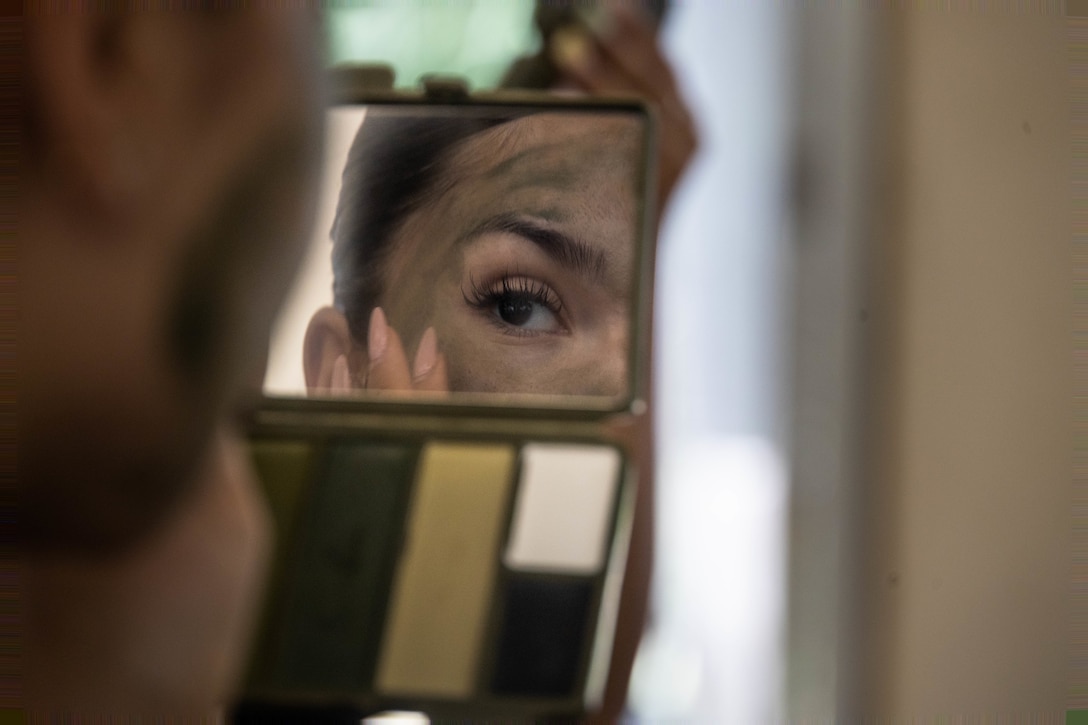A U.S. Marine Corps spouse applies camouflage paint during the Headquarters Battalion Spouse Warrior Day at the Jungle Warfare Training Center, Okinawa, Japan, June 16, 2025. The purpose of the HQBN Spouse Warrior Day is to give spouses an opportunity to participate in activities their Marines experience. (U.S. Marine Corps photo by Cpl. Alexander O. Devereux)
