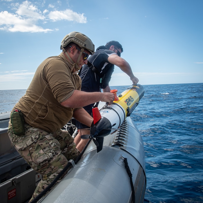 Royal New Zealand Navy Able Hydrographic System Operator Blake Todd, assigned to HMNZS Matataua, and U.S. Navy Robotics Warfare Specialist 2nd Class Roddrick Guerra, assigned to Explosive Ordnance Disposal Mobile Unit 5, recover a Remus 100 autonomous underwater vehicle in a rigid-hull inflatable boat assigned to the Lewis B. Puller-class expeditionary sea base USS John L. Canley (ESB 6) off the coast of Australia during Talisman Sabre, July 18, 2025.