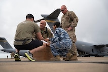 A U.S. Special Operations Forces Operator retrieves a cold chain blood resupply shipment from U.S. Army Sgt. 1st Class Eric Jimenez, medical logistics noncommissioned officer; Royal Australian Air Force Flt. Lt. Pooja Sapkota, scientific officer and pathology advisor, both with the Combined Joint Theatre Medical Component; and a member of the U.S. Air Force’s C-17 Globemaster crew, 535th Airlift Squadron, in Queensland, Australia, during Exercise Talisman Sabre 2025 on July 22, 2025.