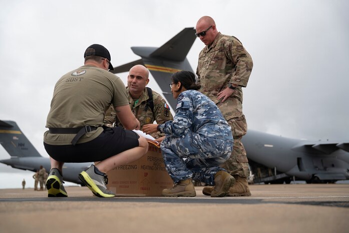 A U.S. Special Operations Forces Operator retrieves a cold chain blood resupply shipment from U.S. Army Sgt. 1st Class Eric Jimenez, medical logistics noncommissioned officer; Royal Australian Air Force Flt. Lt. Pooja Sapkota, scientific officer and pathology advisor, both with the Combined Joint Theatre Medical Component; and a member of the U.S. Air Force’s C-17 Globemaster crew, 535th Airlift Squadron, in Queensland, Australia, during Exercise Talisman Sabre 2025 on July 22, 2025.