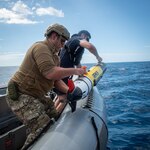 Royal New Zealand Navy Able Hydrographic System Operator Blake Todd, assigned to HMNZS Matataua, and U.S. Navy Robotics Warfare Specialist 2nd Class Roddrick Guerra, assigned to Explosive Ordnance Disposal Mobile Unit 5, recover a Remus 100 autonomous underwater vehicle in a rigid-hull inflatable boat assigned to the Lewis B. Puller-class expeditionary sea base USS John L. Canley (ESB 6) off the coast of Australia during Talisman Sabre, July 18, 2025.