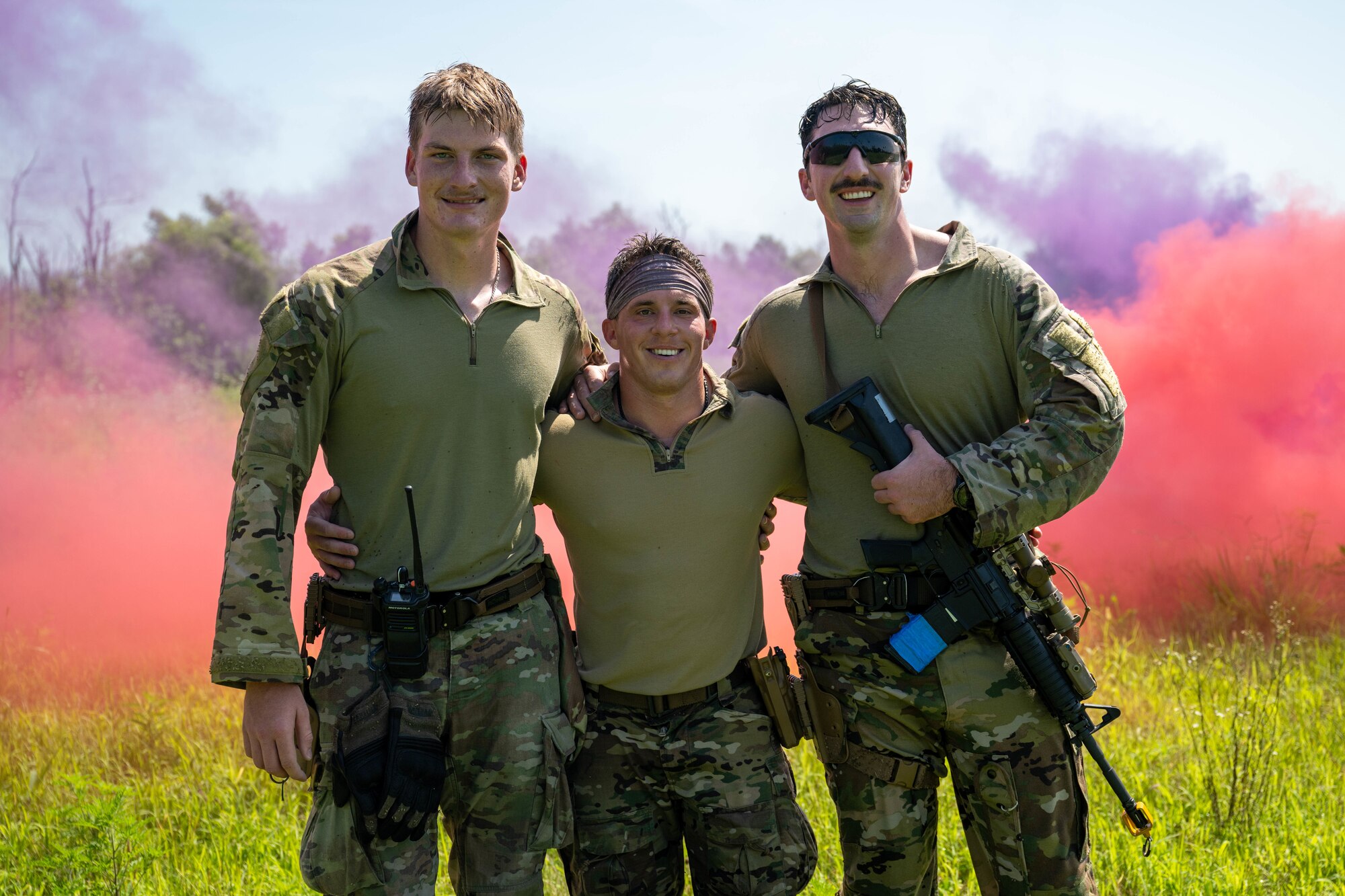 Three military men stand together in uniform to smile for a picture