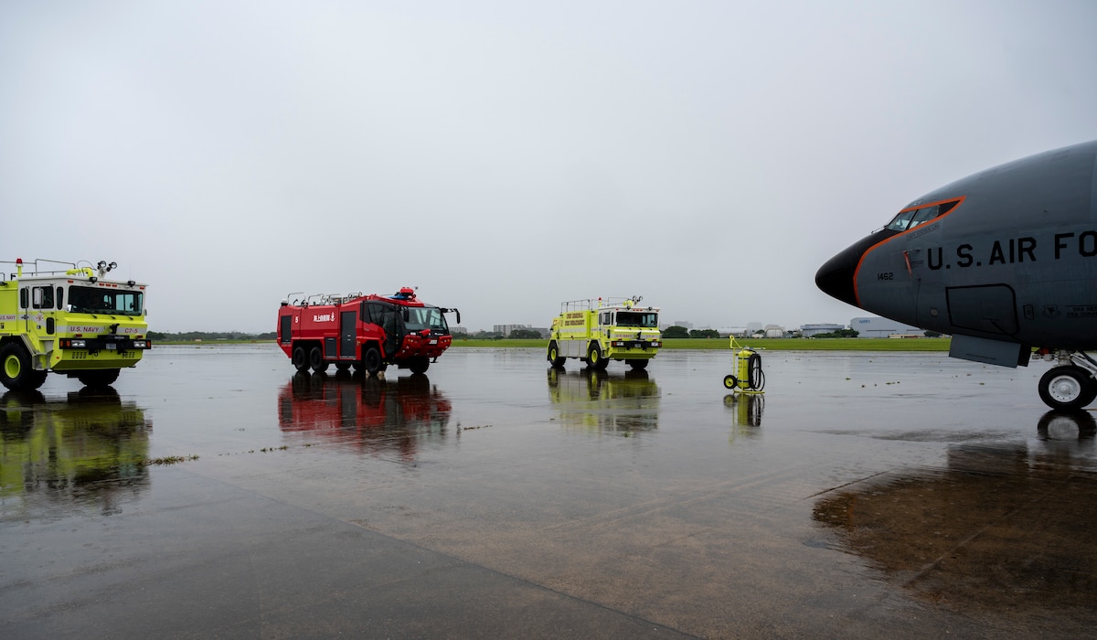 Three aircraft rescue and firefighting trucks park in front of a KC-135 aircraft.