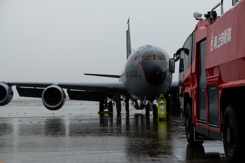 An aircraft rescue and firefighting vehicle is parked in front of a KC-135 Stratotanker aircraft