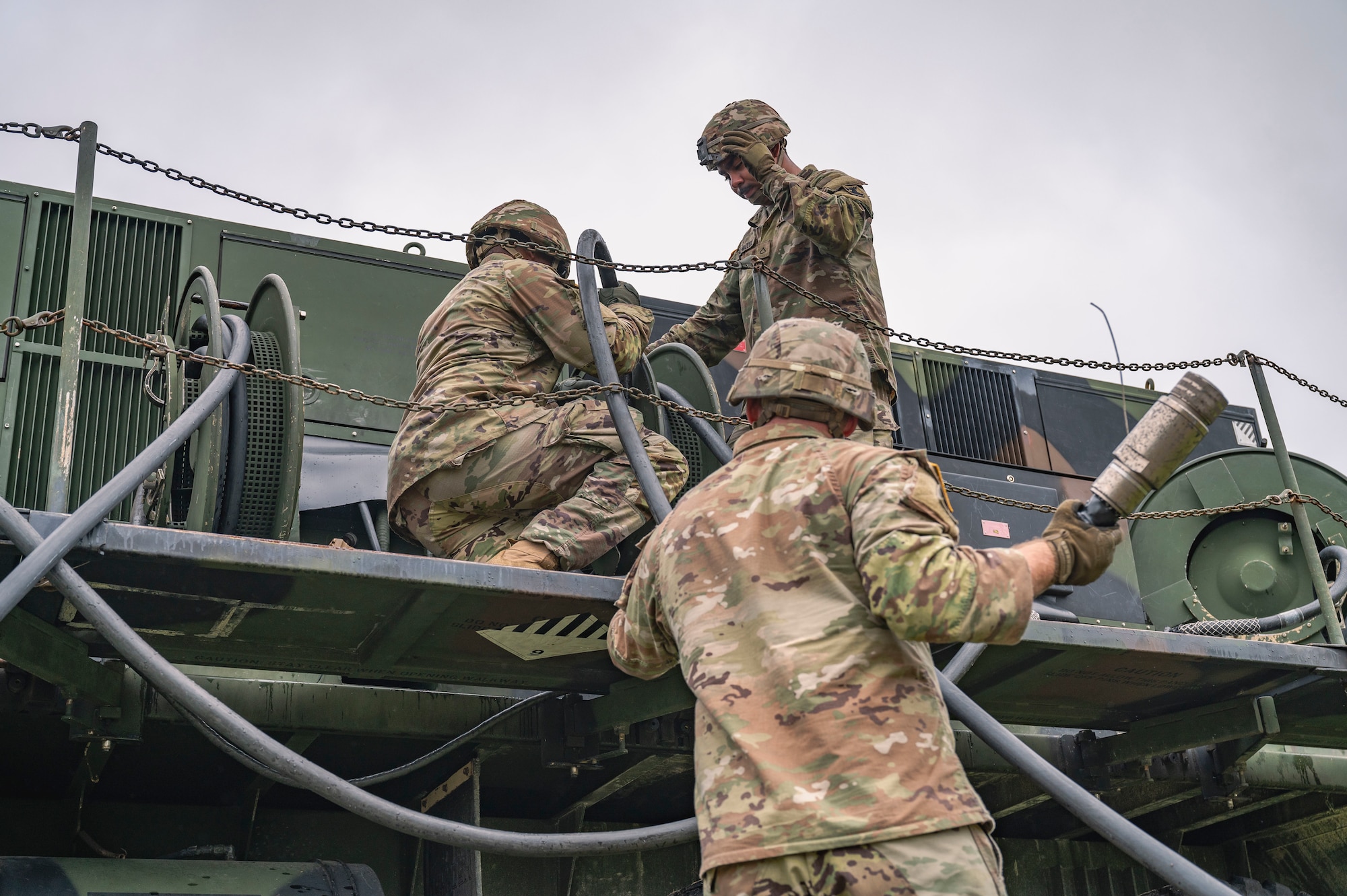 U.S. Army Pfc. Zigmond Berridge, left,1-1 Air Defense Artillery engagement controller, and Pfc. Da’Mario Deal-Maddox, 1-1 ADA vehicle driver, uncoil a hose for Spc. Dustin Crowther, center, 1-1 ADA engagement controller, to connect to an AN/MPQ-65 radar on Kadena Air Base, Japan, July 24, 2025.