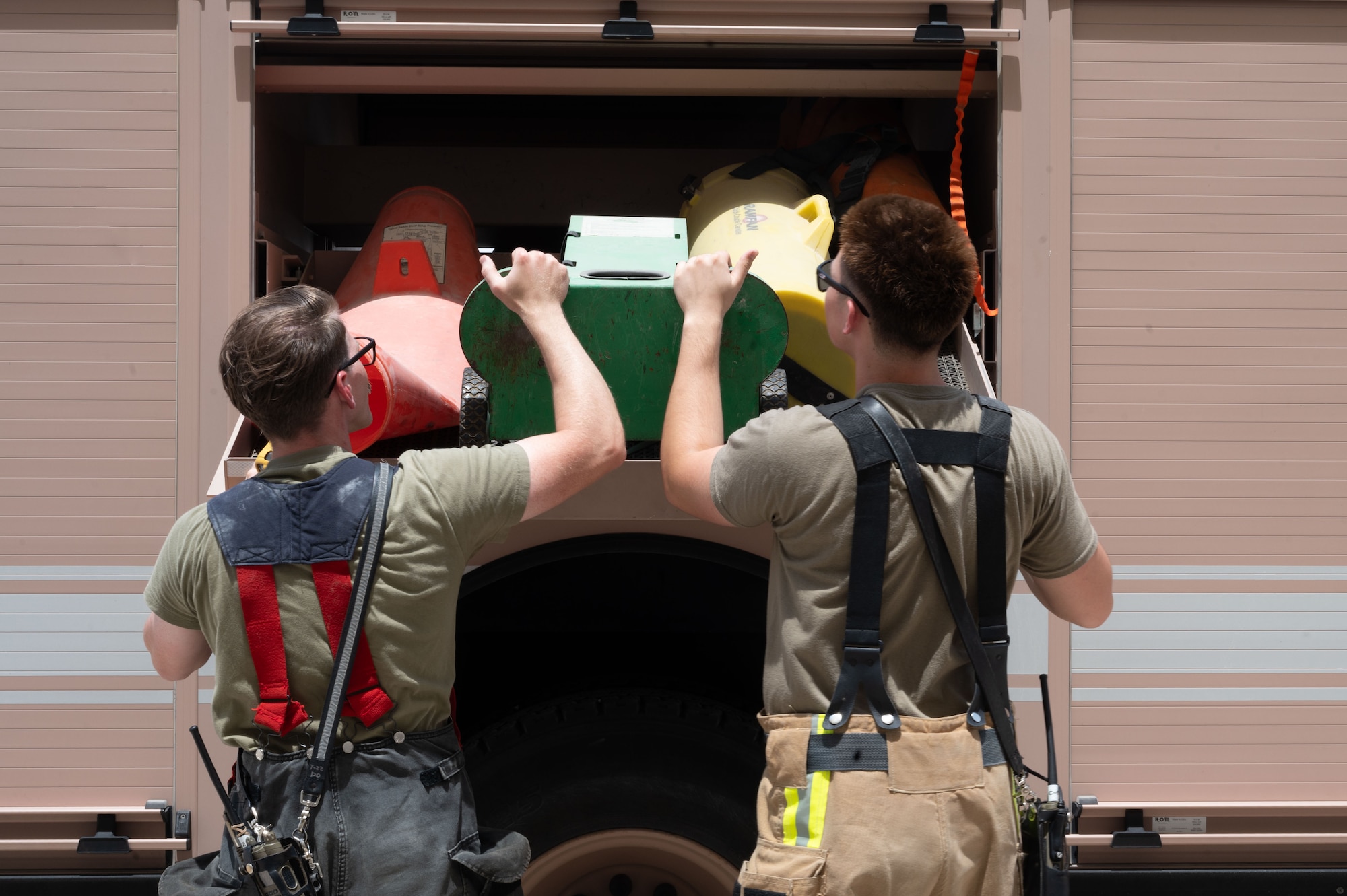 U.S. Air Force Staff Sgt. Taylor Burton, left, and Airman 1st Class Waldon Brisbin, right, both 379th Expeditionary Civil Engineer Squadron firefighters, move equipment from a fire truck during a confined-space extraction exercise within the U.S. Central Command area of responsibility, July 21, 2025. In the event of an accident or emergency where personnel become trapped inside confined spaces, Airmen must be prepared to conduct rescue operations swiftly and effectively. (U.S. Air Force photo by Senior Airman Dieondiere Jefferies)
