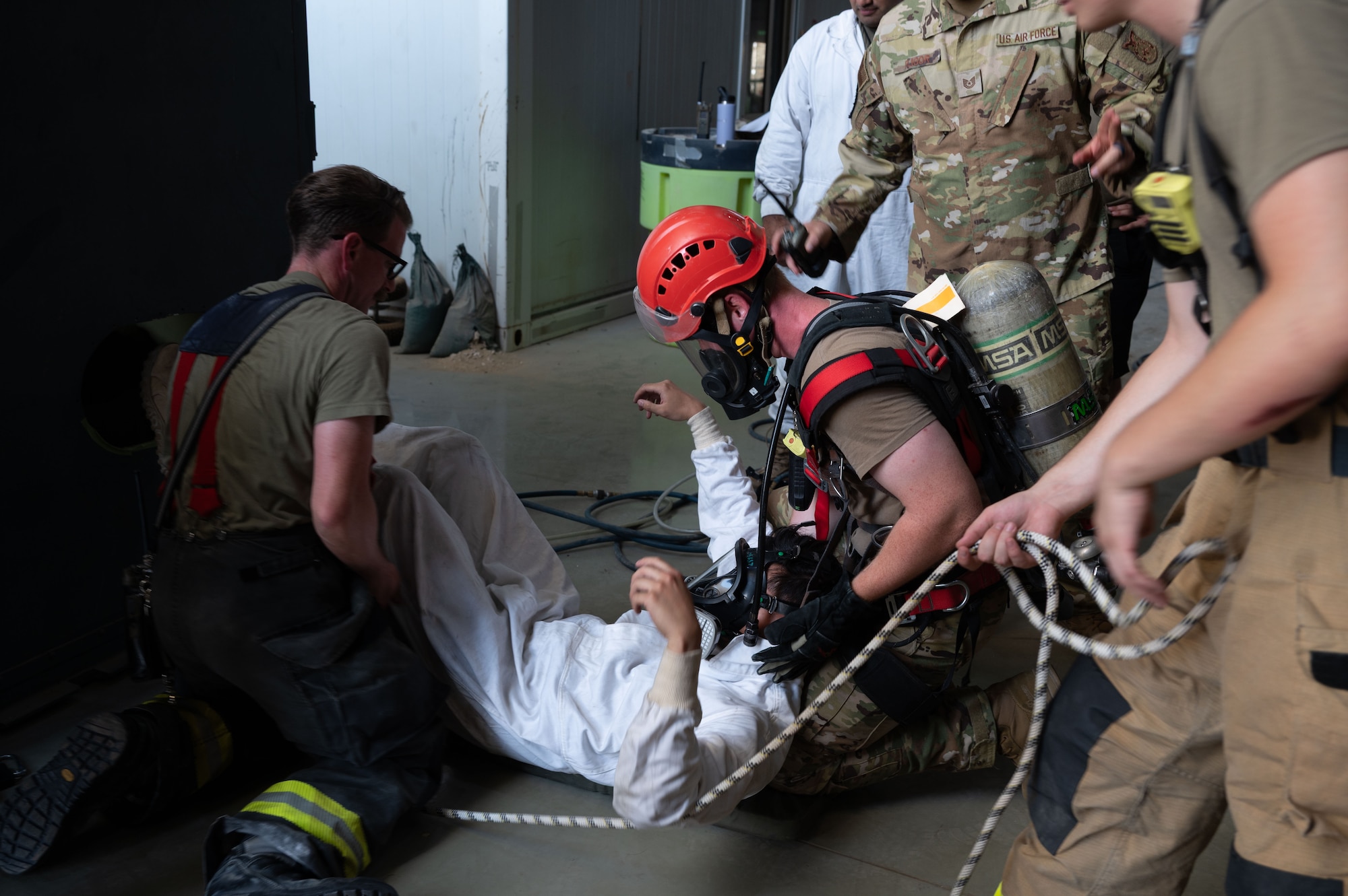 Firefighters assigned to the 379th Expeditionary Civil Engineer Squadron provide aid to a simulated confined-space extraction exercise victim within the U.S. Central Command area of responsibility, July 21, 2025. The 379th ECES is responsible for ensuring the safety of others on base and responding to emergencies. (U.S. Air Force photo by Senior Airman Dieondiere Jefferies)