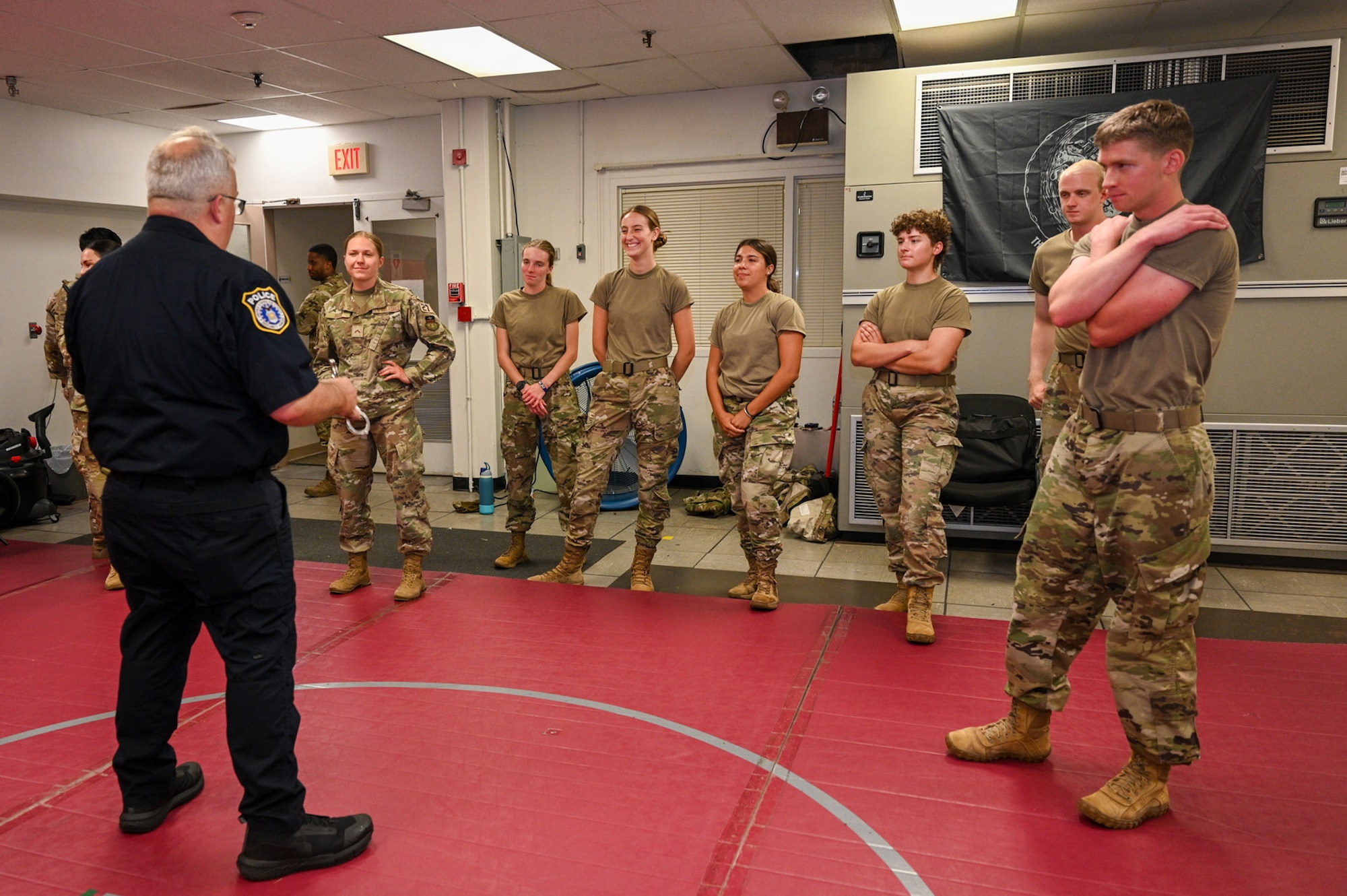 U.S. Air Force Academy cadets gather around Sgt. 1st Class Lance LaRue, a police trainer with the 11th Security Forces Squadron, as he instructs taser exposure training during a USAFA Summer Operations visit at Joint Base Anacostia-Bolling, Washington, D.C., July 16, 2025. Several of the cadets voluntarily experienced the effects of taser deployment during the training, which is a mandatory certification for all Security Forces members. (U.S. Air Force photo by Airman 1st Class Shanel Toussaint)