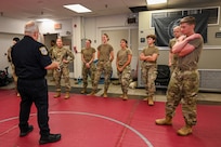 U.S. Air Force Academy cadets gather around Sgt. 1st Class Lance LaRue, a police trainer with the 11th Security Forces Squadron, as he instructs taser exposure training during a USAFA Summer Operations visit at Joint Base Anacostia-Bolling, Washington, D.C., July 16, 2025. Several of the cadets voluntarily experienced the effects of taser deployment during the training, which is a mandatory certification for all Security Forces members. (U.S. Air Force photo by Airman 1st Class Shanel Toussaint)