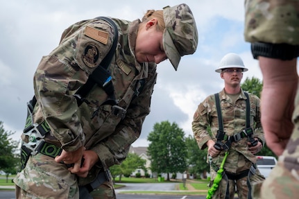 U.S. Air Force Academy Cadet Caitlyn Budd dons a safety harness during a demonstration of 11th Civil Engineer Squadron equipment at Joint Base Anacostia-Bolling, Washington, D.C., July 15, 2025. Cadets visited JBAB as part of USAFA’s Summer Operations program to learn more about officer life and the operational Air Force. (U.S. Air Force photo by Hayden Hallman)
