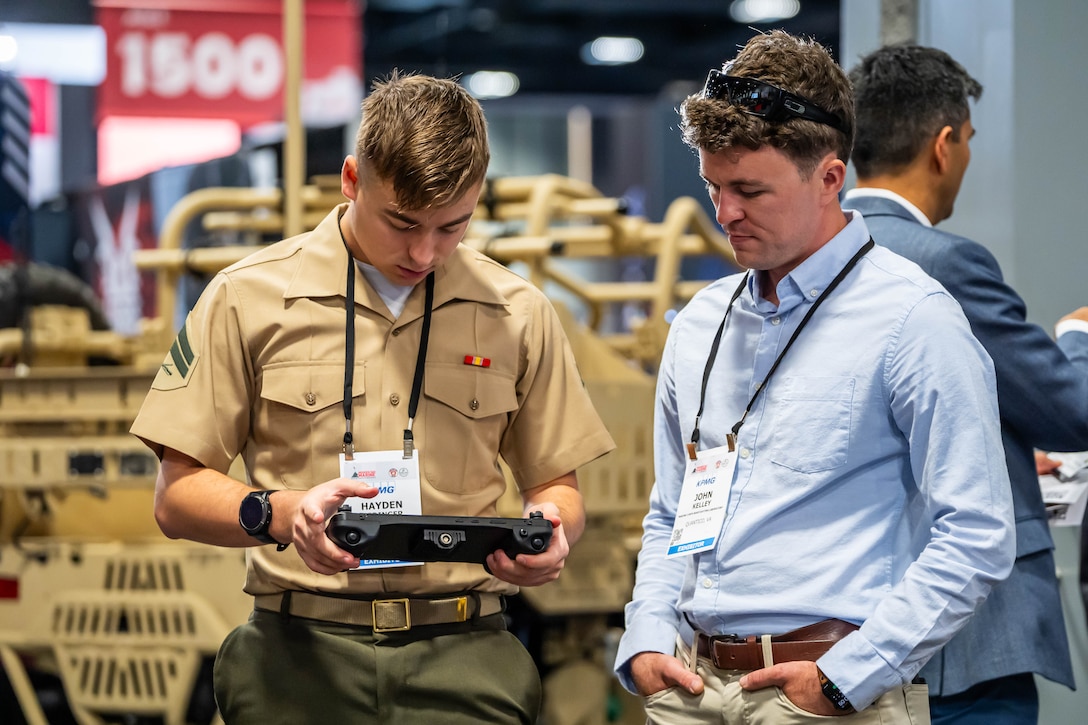 From right, Mr. John Kelley, Marine Corps Warfighting Laboratory, helps U.S. Marine Corps Cpl. Hayden Hedinger, operate a robot dog using a remote controller, during Modern Day Marine at the Walter E. Washington Convention Center, Washington D.C., April 30th, 2025. Modern Day Marine is a military exposition exclusively organized for the Marine Corps to showcase the newest technology and warfighting innovations from amphibious assault vehicles to drones and more. (U.S. Marine Corps photo by Connor Taggart)