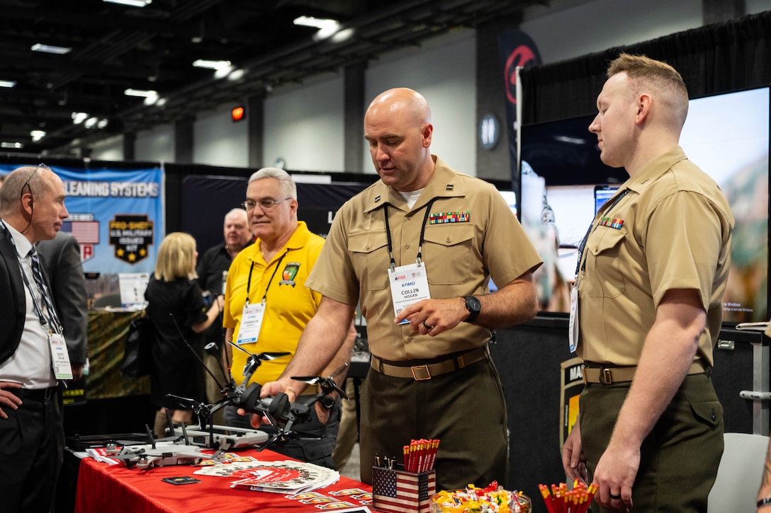 Form left, U.S. Marine Corps Captain Collin Hogan, Marine Corps Warfighting Laboratory (MCWL) Wargaming Division ___, and Capt. John Ryan, MCWL ___, man MCWL's booth during Modern Day Marine at the Walter E. Washington Convention Center, Washington D.C., April 29th, 2025. Modern Day Marine is a military exposition exclusively organized for the Marine Corps to showcase the newest technology and warfighting innovations from amphibious assault vehicles to drones and more. (U.S. Marine Corps photo by Connor Taggart)