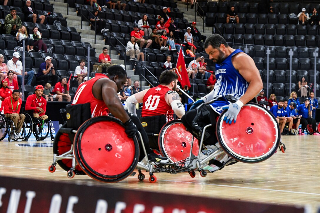 A Marine using a wheelchair blocks a service member using a wheelchair from moving during a rugby match.