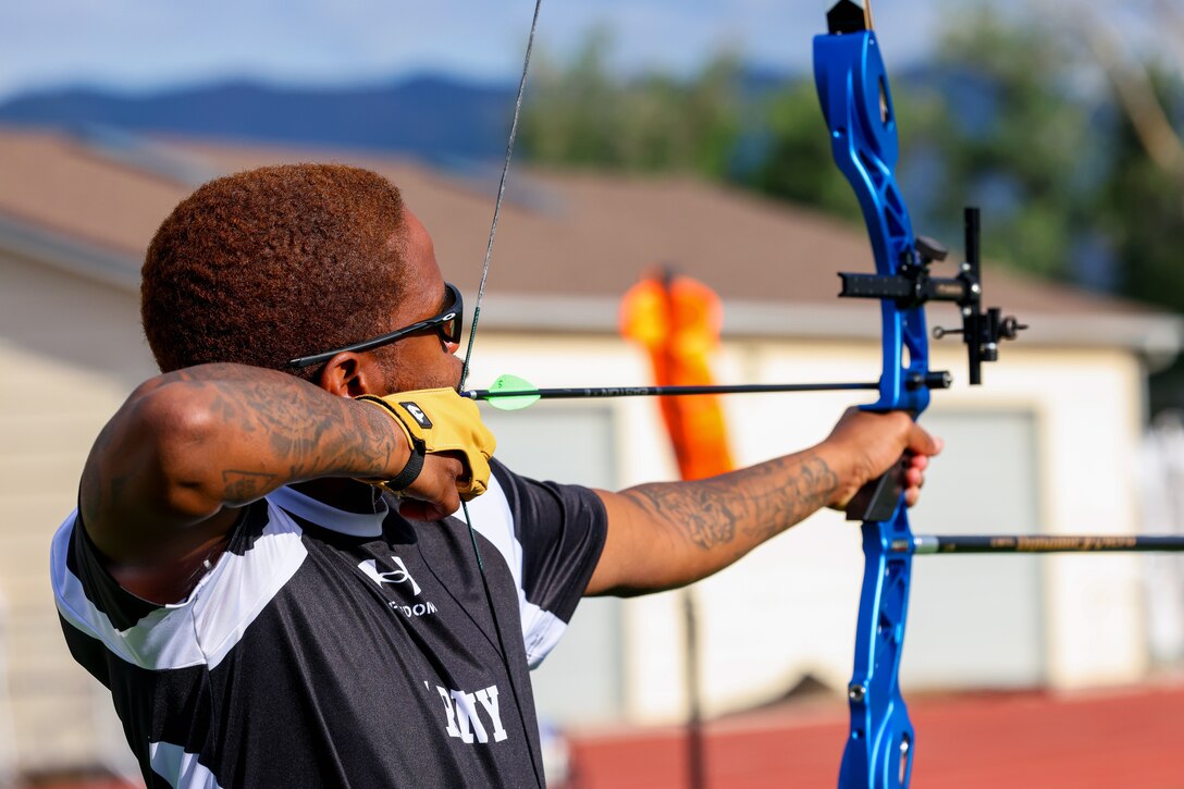 A close-up of a soldier aiming a bow and arrow during a competition.