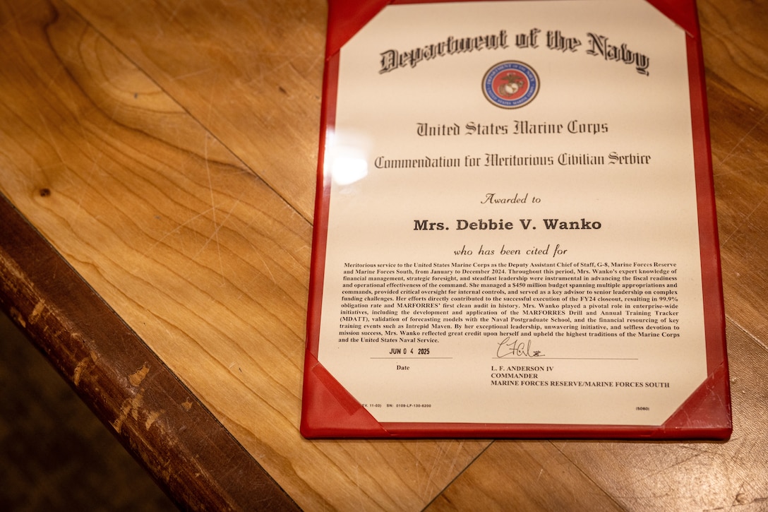 Debbie Wanko, deputy assistant chief of staff G-8, Marine Forces Reserve (MARFORRES), receives the Civilian of the Year award during the Marine Forces Reserve 2024 Civilian of the Year awards at Marine Corps Support Facility, New Orleans, July 23, 2025. Wanko received the senior Civilian of the Year award for her expert knowledge, fiscal readiness and operational effectiveness as she managed a budget of $450 million, Wanko’s expertise directly contributed to a historic fiscal year ending, resulting in a 99.9 percent obligation rate and MARFORRES' first clean audit. (U.S. Marine Corps Photo by Lance Cpl. Edward Spears)