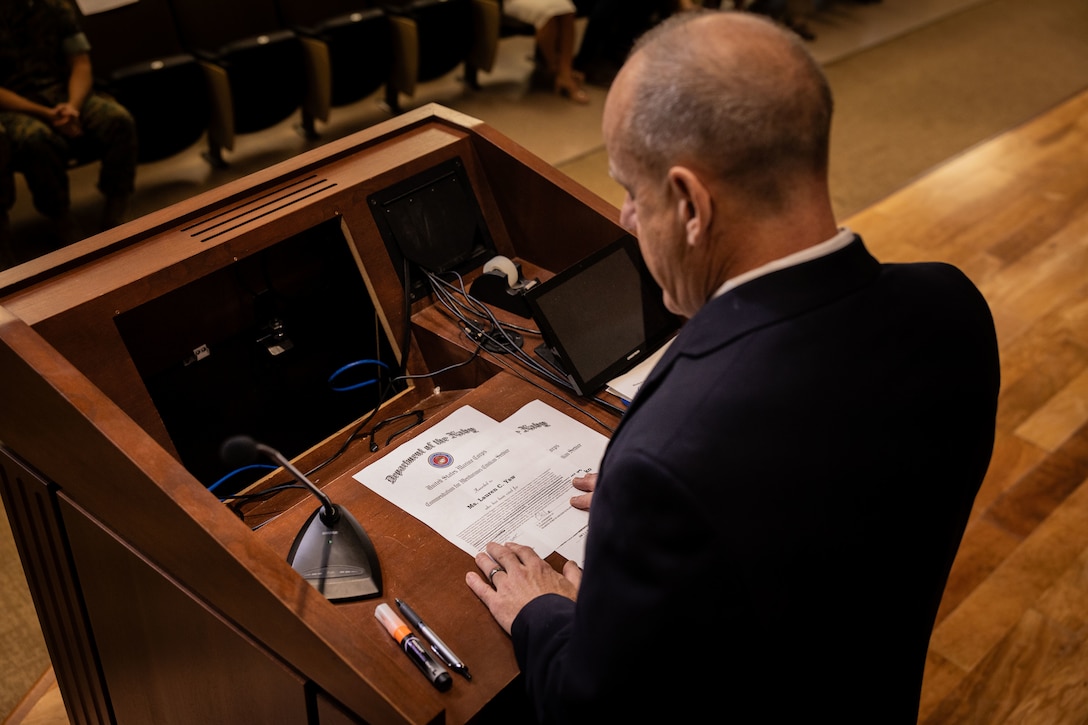 Joe Garcia, assistant deputy chief of staff G-1, Marine Forces Reserve (MARFORRES), reads Lauren Yaw’s the award citation for Lauren Yaw during the Marine Forces Reserve 2024 Civilian of the Year awards at Marine Corps Support Facility, New Orleans, July 23, 2025. Ms. Yaw is the muster program manager for the Marine Corps Individual Support Activity, which oversees the Individual Readiness Reserve program for MARFORRES. The Civilian of the Year awards recognizes civilians whose outstanding service and dedication have made a long-lasting impact at MARFORRES. (U.S. Marine Corps Photo by Lance Cpl. Edward Spears)