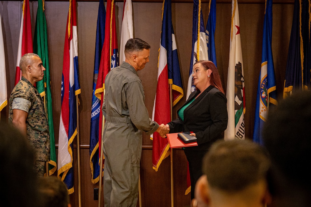 U.S. Marine Corps Lt. Gen. Leonard Anderson IV, middle, commander of Marine Forces Reserve (MARFORRES) and Marine Forces South, shakes hands with Lauren Yaw, right, muster program manager, Marine Corps Individual Support Activity, MARFORRES, during the Marine Forces Reserve 2024 Civilian of the Year awards at Marine Corps Support Facility New Orleans, July 23, 2025. Yaw received the junior Civilian of the Year award for executing and planning 30 Inactive Ready Reserve musters for Marines worldwide. (U.S. Marine Corps Photo by Lance Cpl. Edward Spears)