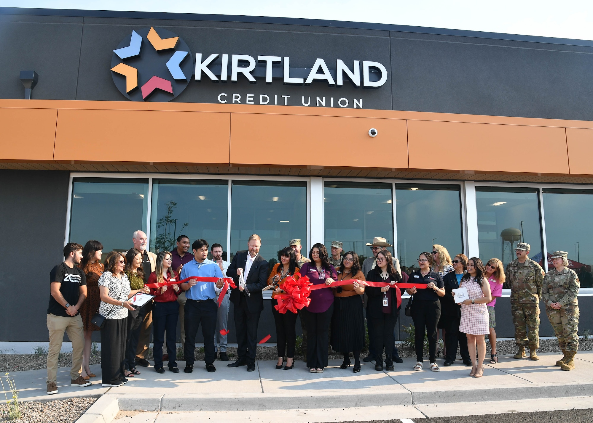people cutting a ribbon in front of a building