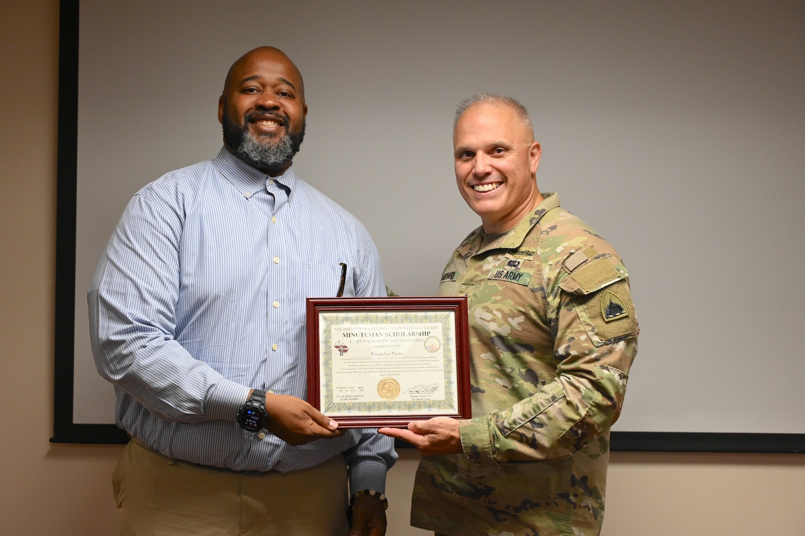 A representative from Lawrence Dunbar High School receives a scholarship certificate on behalf of Brooklyn Payne, a graduate of Paul Laurence Dunbar High School, during a Minuteman Scholarship ceremony at the D.C. Armory in Washington, D.C., on July 18, 2025. Payne received a three‑year scholarship to attend Howard University with plans to commission into the Medical Services Corps.