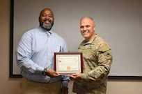 A representative from Lawrence Dunbar High School receives a scholarship certificate on behalf of Brooklyn Payne, a graduate of Paul Laurence Dunbar High School, during a Minuteman Scholarship ceremony at the D.C. Armory in Washington, D.C., on July 18, 2025. Payne received a three‑year scholarship to attend Howard University with plans to commission into the Medical Services Corps.