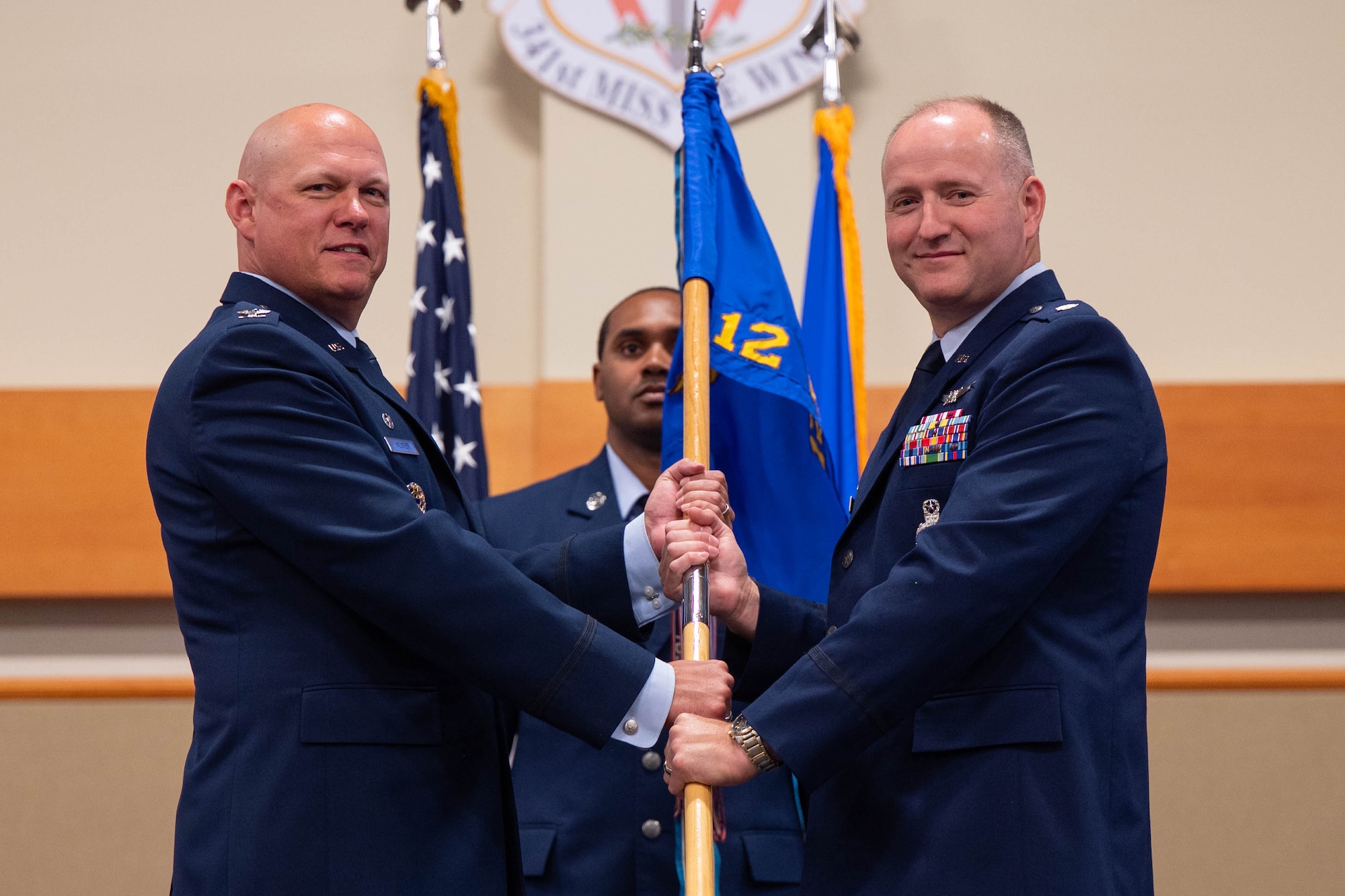 Men in uniform hold a flag during a ceremony.