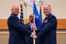 Men in uniform hold a flag during a ceremony.