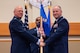 Men in uniform hold a flag during a ceremony.