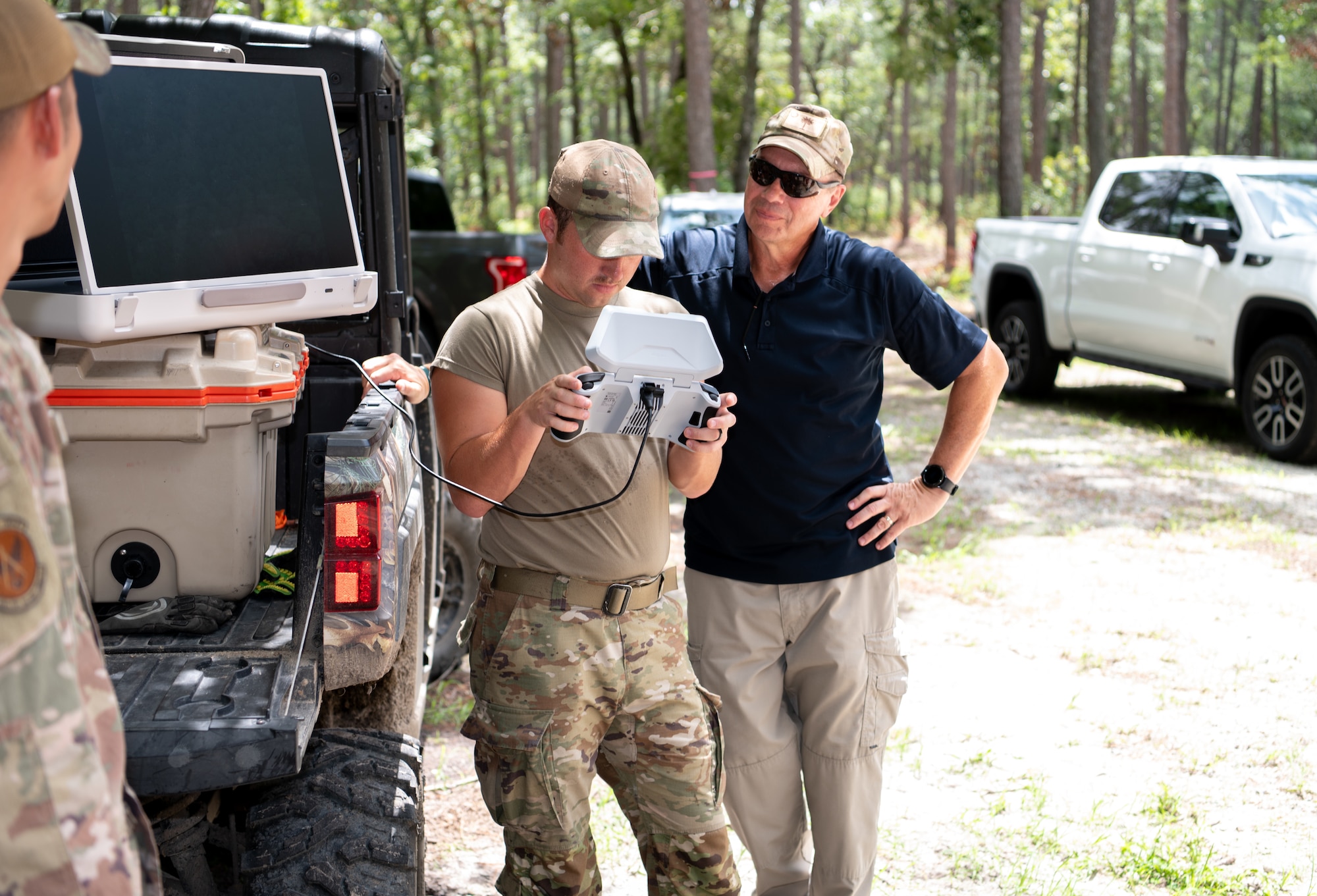 Airmen learn how to fly a small drone in the woods.