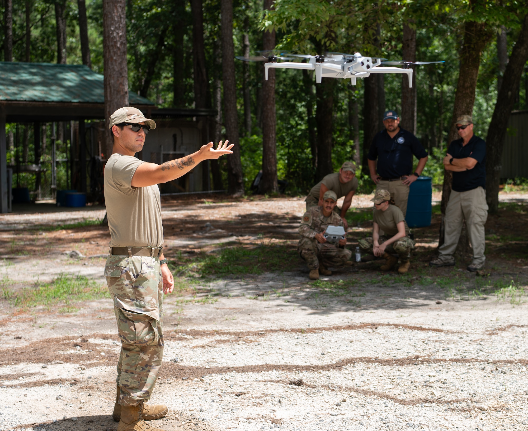 Airmen learn how to use a small drone in the woods