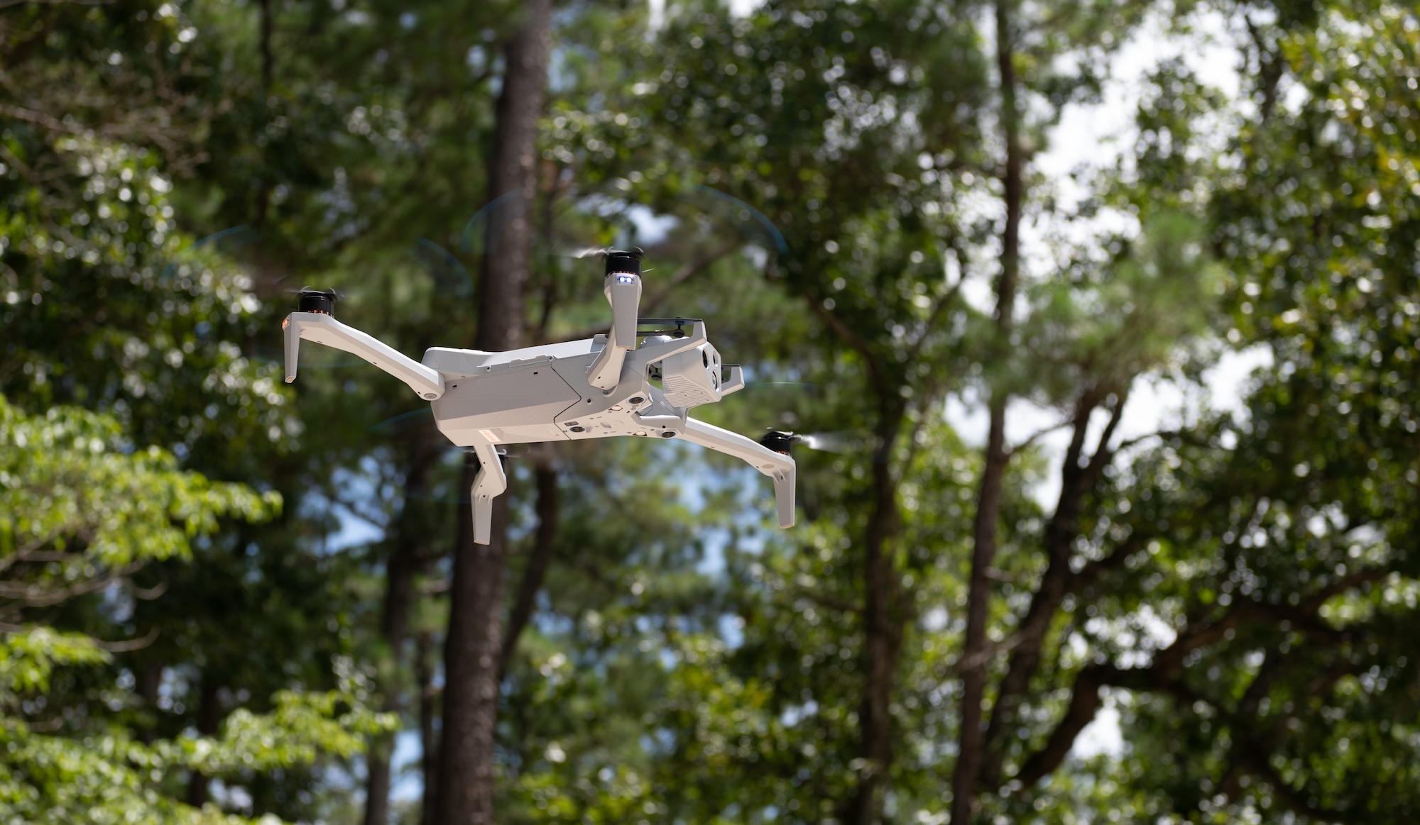Airmen learn how to use a small drone in the woods