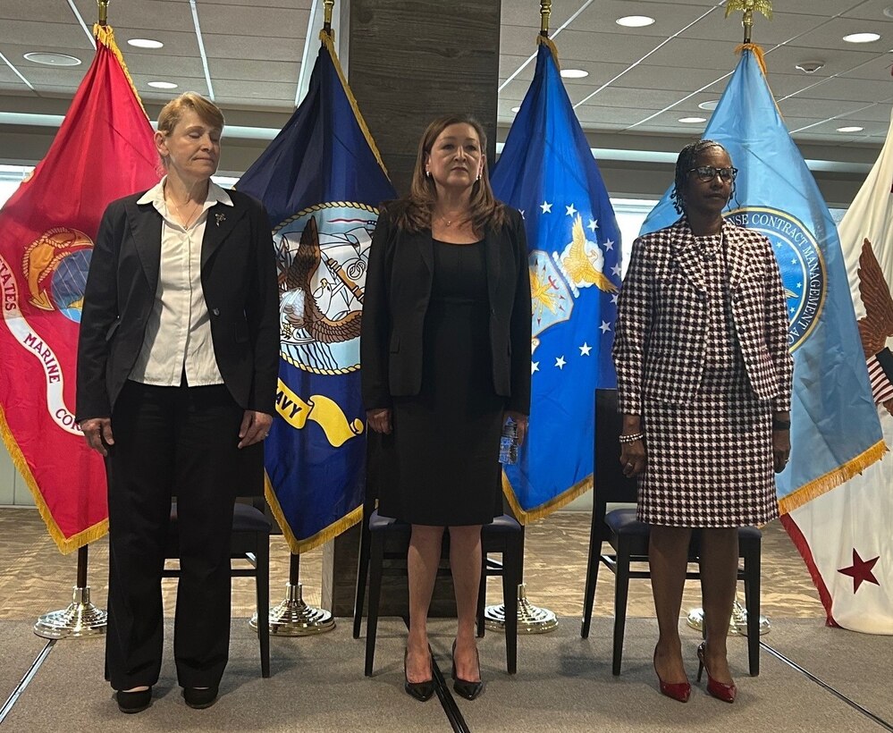 Three people standing for the national anthem.