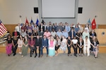 Group poses ahead of graduation reception on auditorium stage.