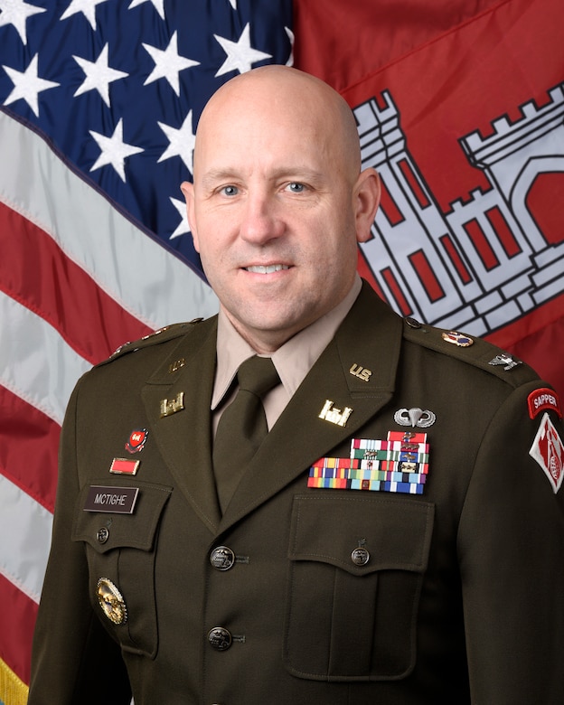 Portrait of Col. Robert M. McTighe with United States and U.S. Army Corps of Engineers flags behind him.
